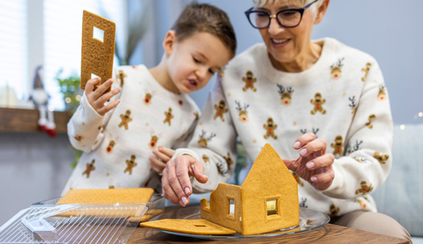 En äldre kvinna och en liten pojke som bygger ett pepparkakshus