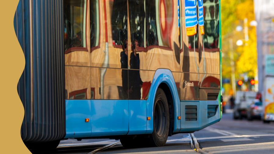 En blå buss svänger på en väg.