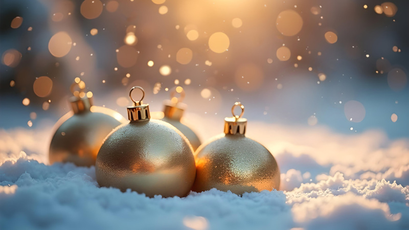 Tre glänsande julprydnader i snön