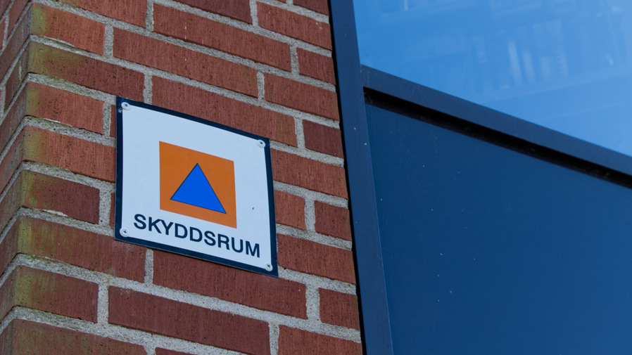 En skyddsrumsskylt på fasaden på ett hus.