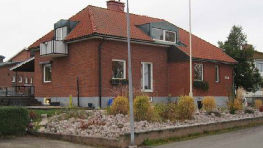 Ett rött tegelhus som ligger i hörnet av en gata