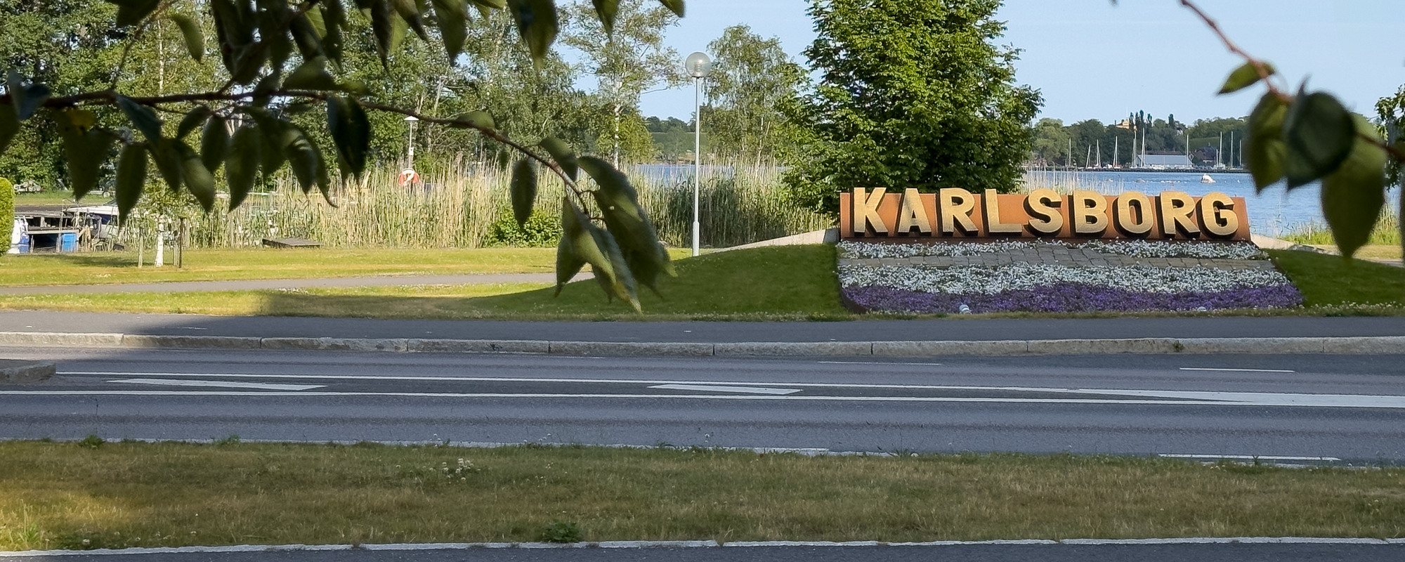 En skylt med texten "Karlsborg" med vatten i bakgrunden.