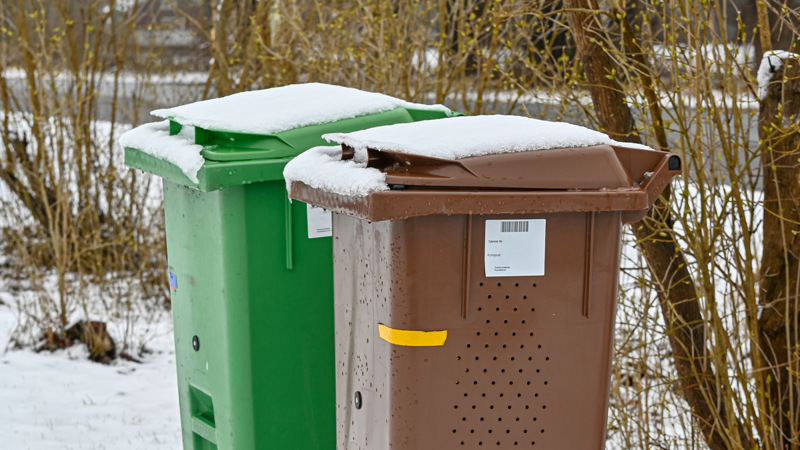 Två soptunnor som står bredvid varandra i ett vinterlandskap.