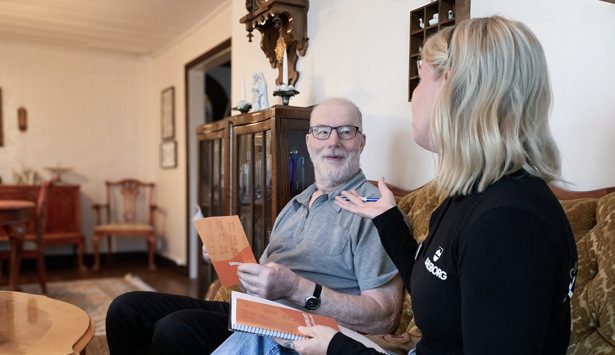 En kvinna sitter i en soffa och pratar med en man