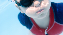 Liten pojke simma runder vattnet